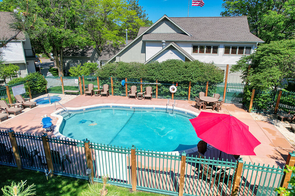 a pool with chairs and umbrella in a backyard