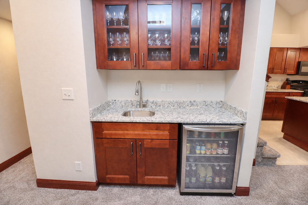 a bar with a fridge and wine glasses